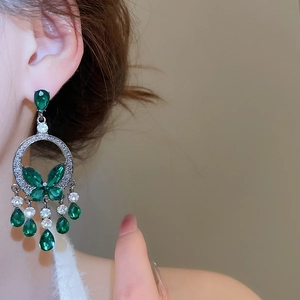 Detail of luxury teardrop green crystal butterfly fringe earrings worn on model ear
