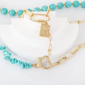 Detailed close-up of turquoise beads with heart clasp and golden rose charm necklace
