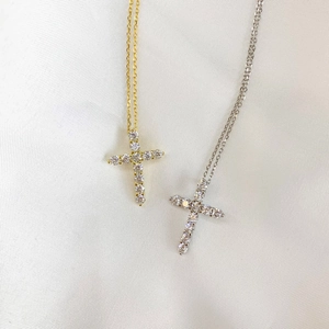 Detailed macro view of gold and silver cross necklaces with inlaid stones on silk