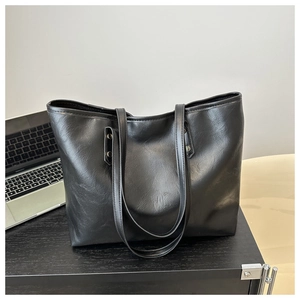 Detail of silver rivets on black leather tote bag in a professional office setting