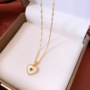 Detailed close-up of heart pendant with green gemstone and gold wave chain in a jewelry box