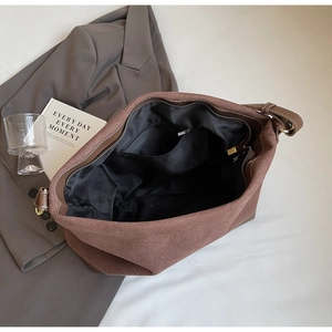 Detail view of large brown suede tote bag with white stitching and zipper closure