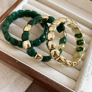 Detailed close-up of three chunky geometric stretch bracelets in gold and peacock green resin