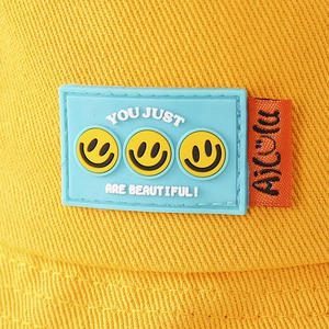 Dettaglio cappello alla pescatora giallo per bambini con simpatica toppa smiley