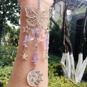 Detail of silver suncatcher featuring butterfly and celestial pendants with purple crystals