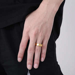 Nahaufnahme eines minimalistischen breiten Goldrings aus Edelstahl für Herren am Finger