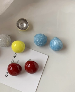 Détails de boucles d'oreilles boules colorées en résine rouge, jaune et motif marbre
