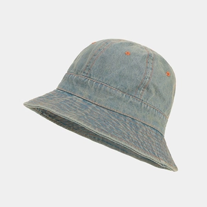 Détail d'un bob en jean bleu clair avec des surpiqûres orange contrastées et textures