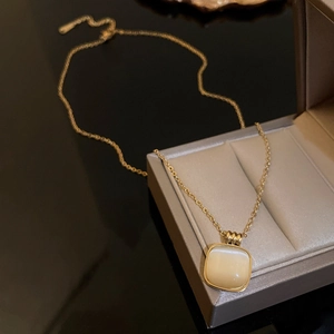 Vue macro du collier en acier titane doré avec pendentif opale carrée dans un écrin