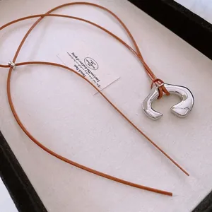 Minimalist silver irregular C-shaped pendant necklace with adjustable brown leather cord