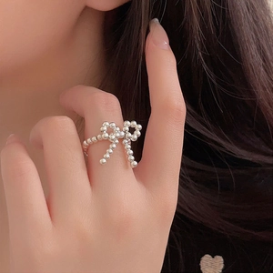 Close-up of S925 sterling silver beaded bow ring worn on model finger for fashion detail