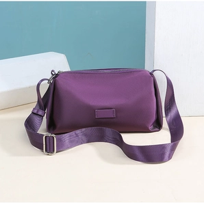 Detalle del bolso bandolera de nailon morado con correa ancha y parche rectangular sencillo