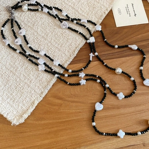 Detail of layered beaded necklace with black crystals, pearls, and star heart charms