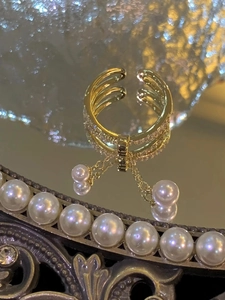 Detailed macro view of gold-plated layered ring with sparkling zircons and pearl tassels