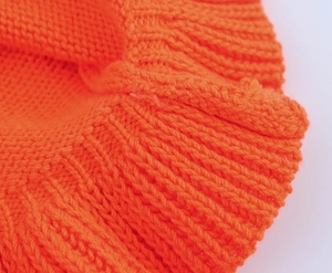 Vue détaillée de la texture tricotée côtelée orange vif et des coutures du vêtement