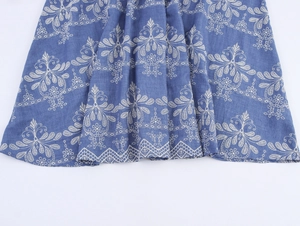 Détail de l'ourlet de robe bleue avec broderie florale blanche et bordure ondulée