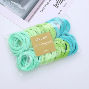 Detailed set of assorted green elastic hair bands in transparent packaging on white background