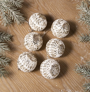 Macro detail of six white frosted Christmas balls with gold sequins on wood background
