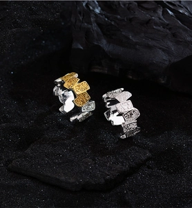 Detailed view of silver and gold rings with carved patterns on black rock background