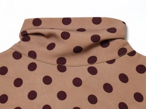 Detail of camel midi dress featuring high neck collar and brown polka dot knit pattern