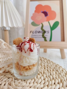 Detail of strawberry chocolate sundae scented candle in glass with realistic cream and biscuits