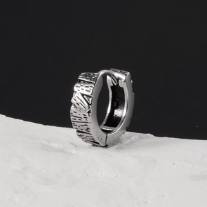 Détail d'une boucle d'oreille argentée avec texture météorite sur socle de pierre