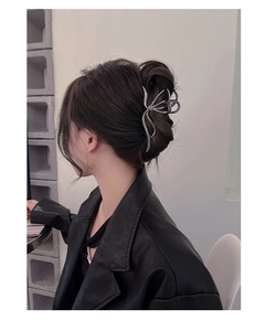 Detailed view of a silver butterfly metal hair claw clip worn on a low bun hairstyle