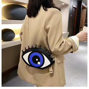 Detailed view of the unique big eye shoulder bag with lashes and golden chain strap