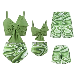 Flat lay of green swirl print matching family swimwear set with high waist and swim trunks