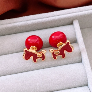 Macro detail of 18K gold plated horse stud earrings with red enamel and pearl accent