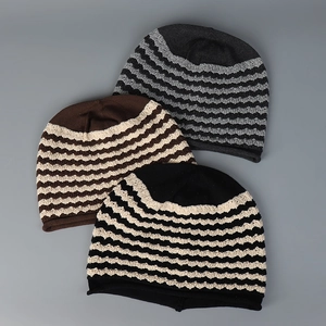 Detailed knit texture of wavy striped slouchy beanies in grey, tan, and black colors