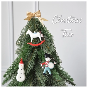 Detailed view of Christmas tree ornaments featuring a wooden horse, snowman, and soldier
