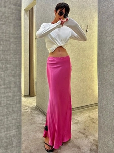 Gonna lunga a sirena in raso rosa fucsia abbinata a un top bianco corto a maniche lunghe