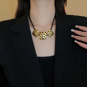 Detail der Vintage-Halskette mit Leopardenmuster, goldenen Anhängern und schwarzer Kordel