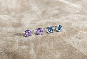 Macro view of 925 sterling silver four-prong earrings with purple and white zircon stones