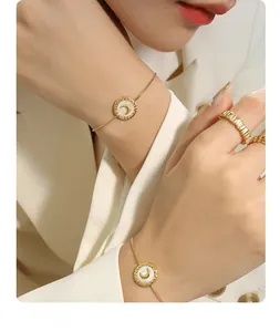 Detail of a gold moon bracelet with shell inlay and a sparkling zircon ring on hand