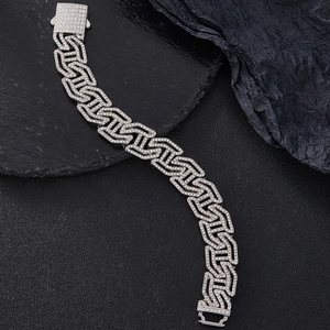 Close-up of silver Cuban link bracelet with iced out crystals on dark stone texture