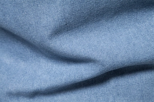 Macro view of light blue denim twill fabric texture and fine fiber weaving details