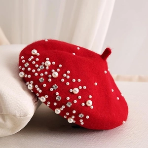 Detailed view of a red wool beret with luxury white pearls and sparkling rhinestone accents