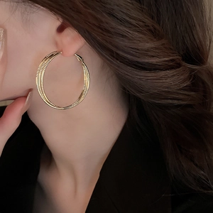 Gros plan de boucles d'oreilles créoles dorées multicouches avec gravure en spirale