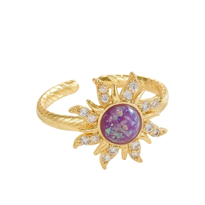 Adjustable gold ring featuring a sunburst crown with purple opal and sparkling crystals