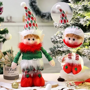 Christmas elf doll ornament with retractable legs standing on a snowy festive tabletop