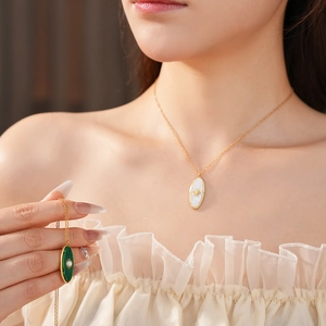 Close-up of vintage oval gold necklace with mother of pearl and malachite sun pendants