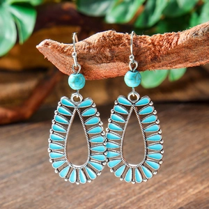 Detailed close-up of Bohemian teardrop earrings hanging on a natural wooden branch