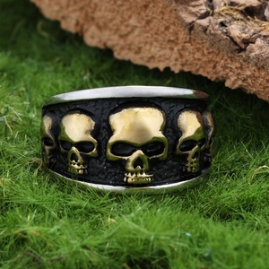 Macro view of wide punk skull rings in gold and silver finish on mossy wood