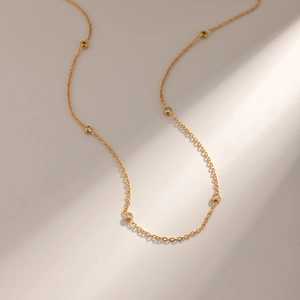 Minimalist gold necklace with small round zircon stones on a refined gold chain link