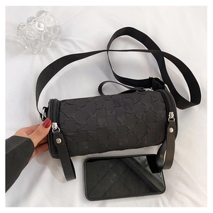 Macro shot of black cylinder bag with woven texture, metal zipper and nylon strap