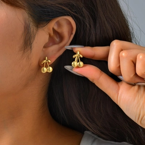 Polished gold cherry shaped stainless steel earrings shown as a worn pair on model