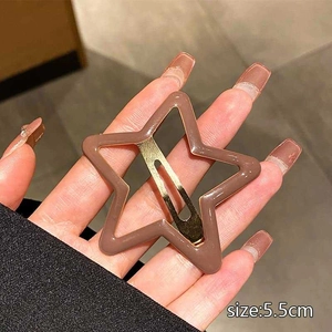 Close-up of 5.5cm brown star-shaped hair clip held in hand showing metallic clasp