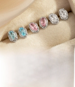 Macro shot of oval zircon cartilage studs in blue and pink with silver titanium steel bars
